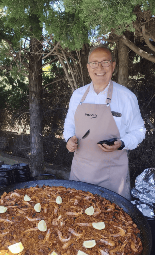 Pepe Orts smiling behind a giant seafood fideuà at a wedding day-after party in Benidorm
